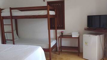 A room with bunk beds, a small table with a TV, and a refrigerator.
