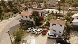 A hotel with a paved street, parked cars, and surrounding greenery. - Villa Pontinha (Amontada)