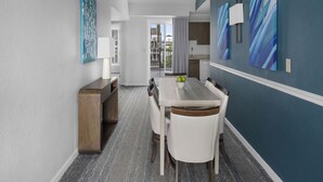 A modern dining area with a wooden table and white chairs, a blue accent wall, and a view of the outside. - Harborfront Charm at Wyndham Onshore Resort (Newport)