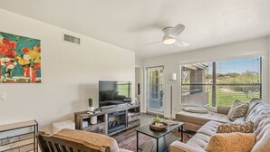 A modern living room with a flat-screen TV, comfortable seating, a fireplace, and large windows offering a view of the outdoors. - Exceptional upgrades makes for a perfect short or long term stay (TUCSON)