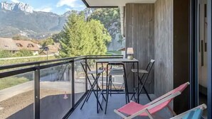 A balcony with a table and chairs, a glass railing, and a view of mountains. - Le cosy de Duingt, charmant appartement à 150m du lac (Duingt)