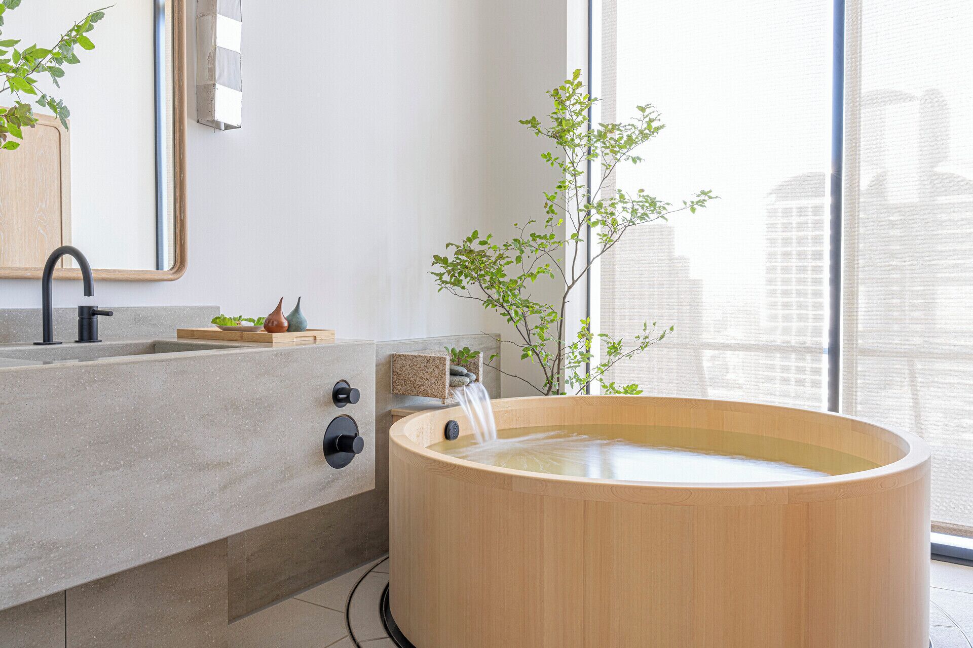 A modern bathroom with a wooden bathtub, a sink with a faucet, and a mirror.