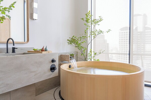 A modern bathroom with a wooden bathtub, a sink with a faucet, and a mirror.