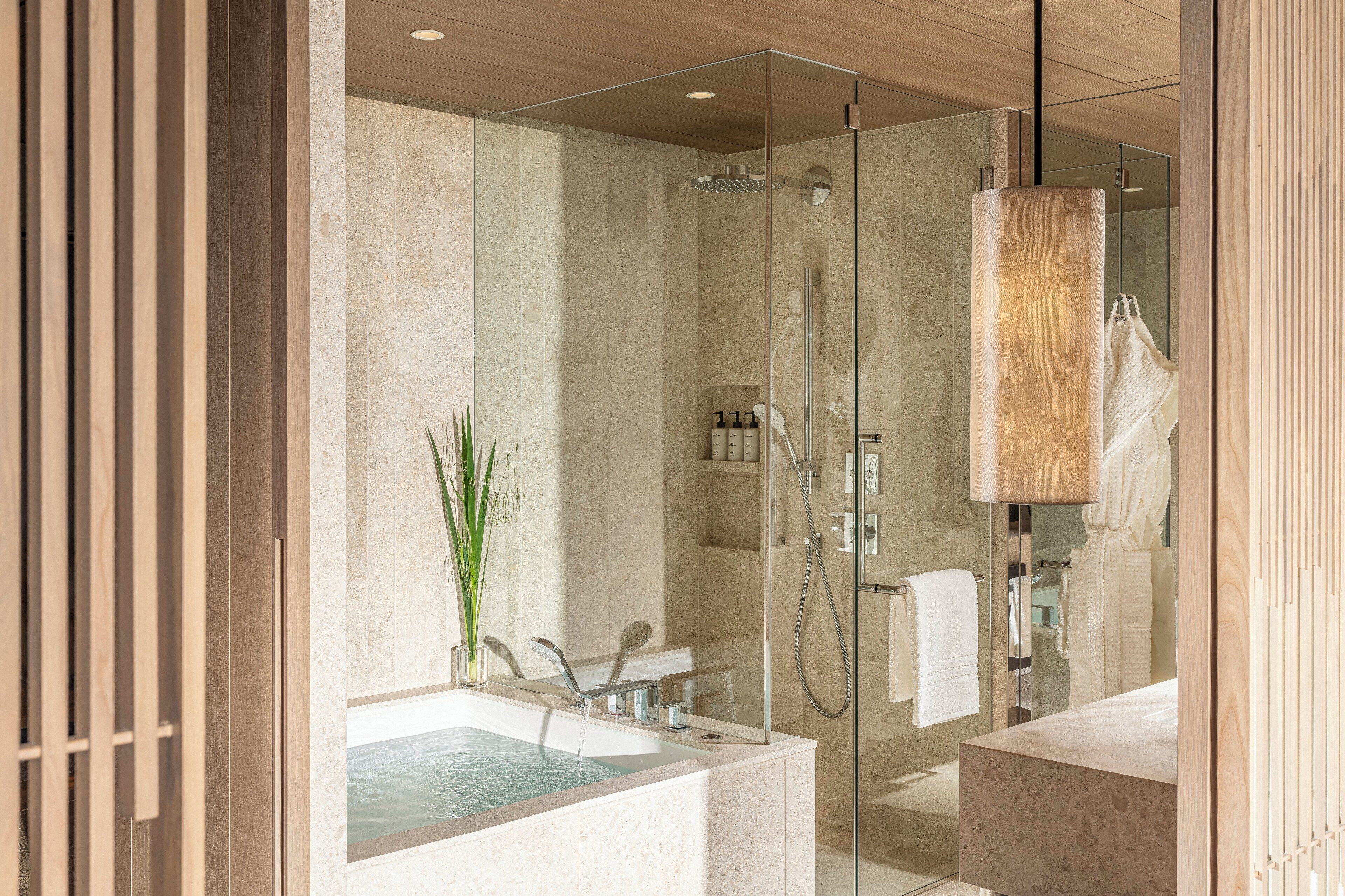 A modern bathroom with a glass-enclosed shower, a bathtub, and a large mirror.