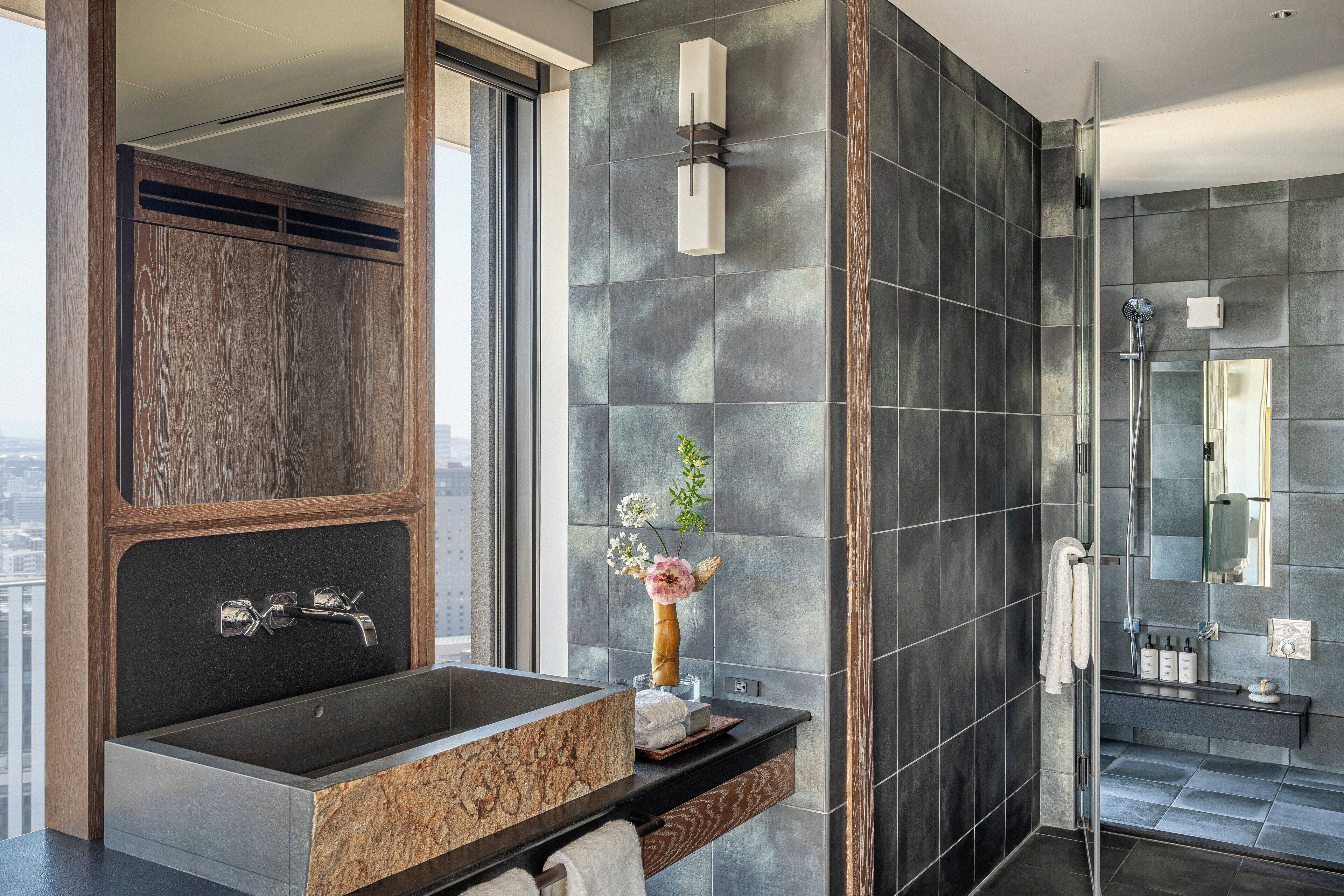 A modern bathroom with a large sink, a mirror, and a shower area.