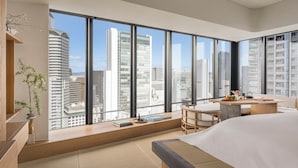 A modern hotel room with large windows, a bed, a desk, and a view of city buildings. - Four Seasons Hotel Osaka (Osaka)