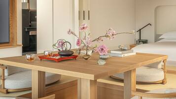A wooden table with a vase of pink flowers, a teapot, and a tray with a cup of tea.