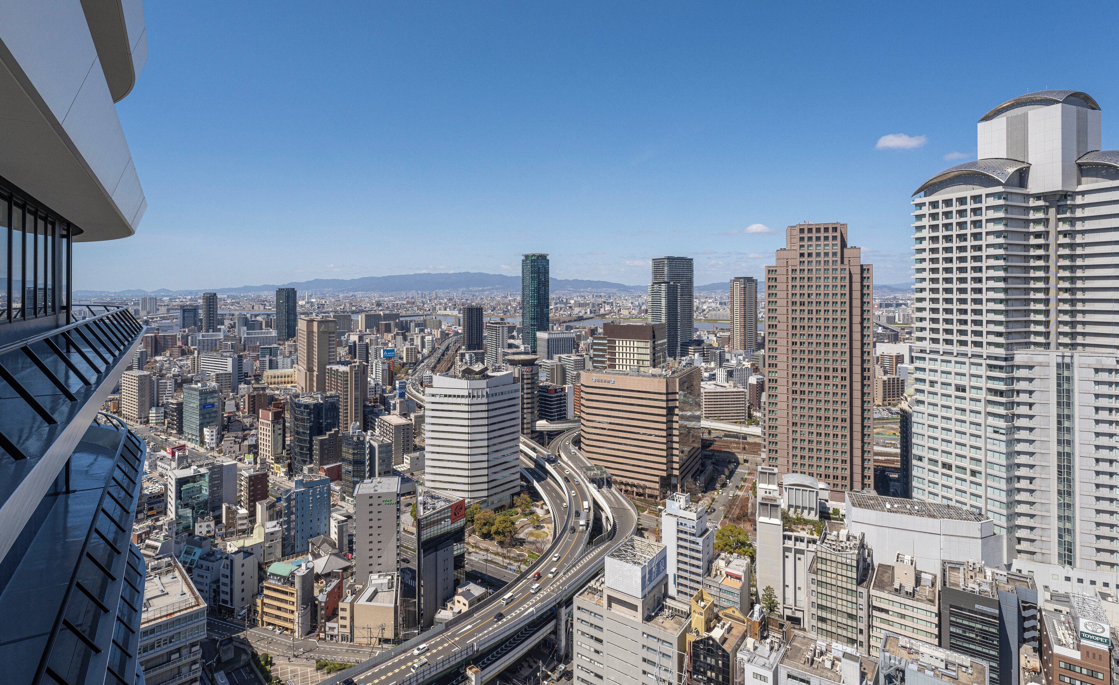 A cityscape with high-rise buildings, a highway, and a clear sky.