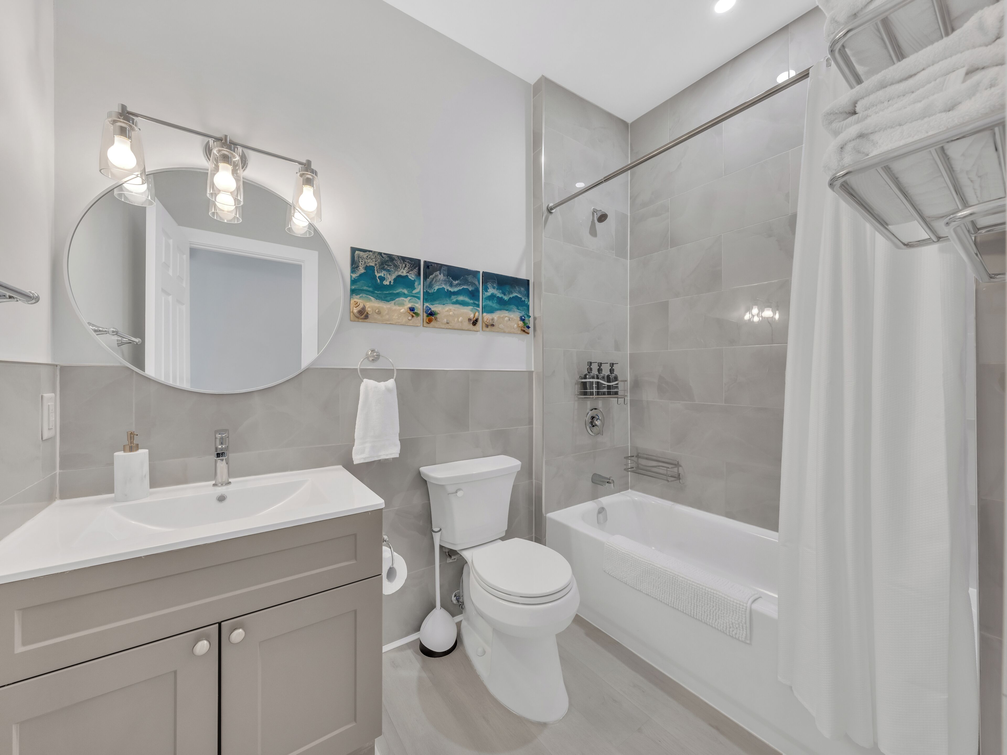 Une salle de bain moderne équipée d’un meuble-lavabo, de toilettes, d’une baignoire et d’une douche.