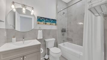 Une salle de bain moderne équipée d’un meuble-lavabo, de toilettes, d’une baignoire et d’une douche.