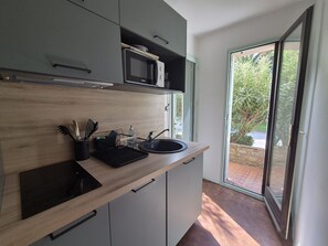 A modern kitchen with a microwave, sink, and dish drying rack.