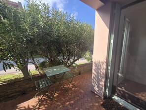 A patio with a table and chairs, a small tree, and a building entrance.