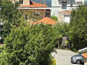 Stroll through the charming residential area surrounded by lush greenery and a beautiful building with a red-tiled roof.