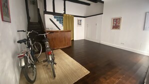 Ein geräumiger Raum mit Holzboden, einem Fahrrad, einer Treppe und einem Bett mit Kopfteil.