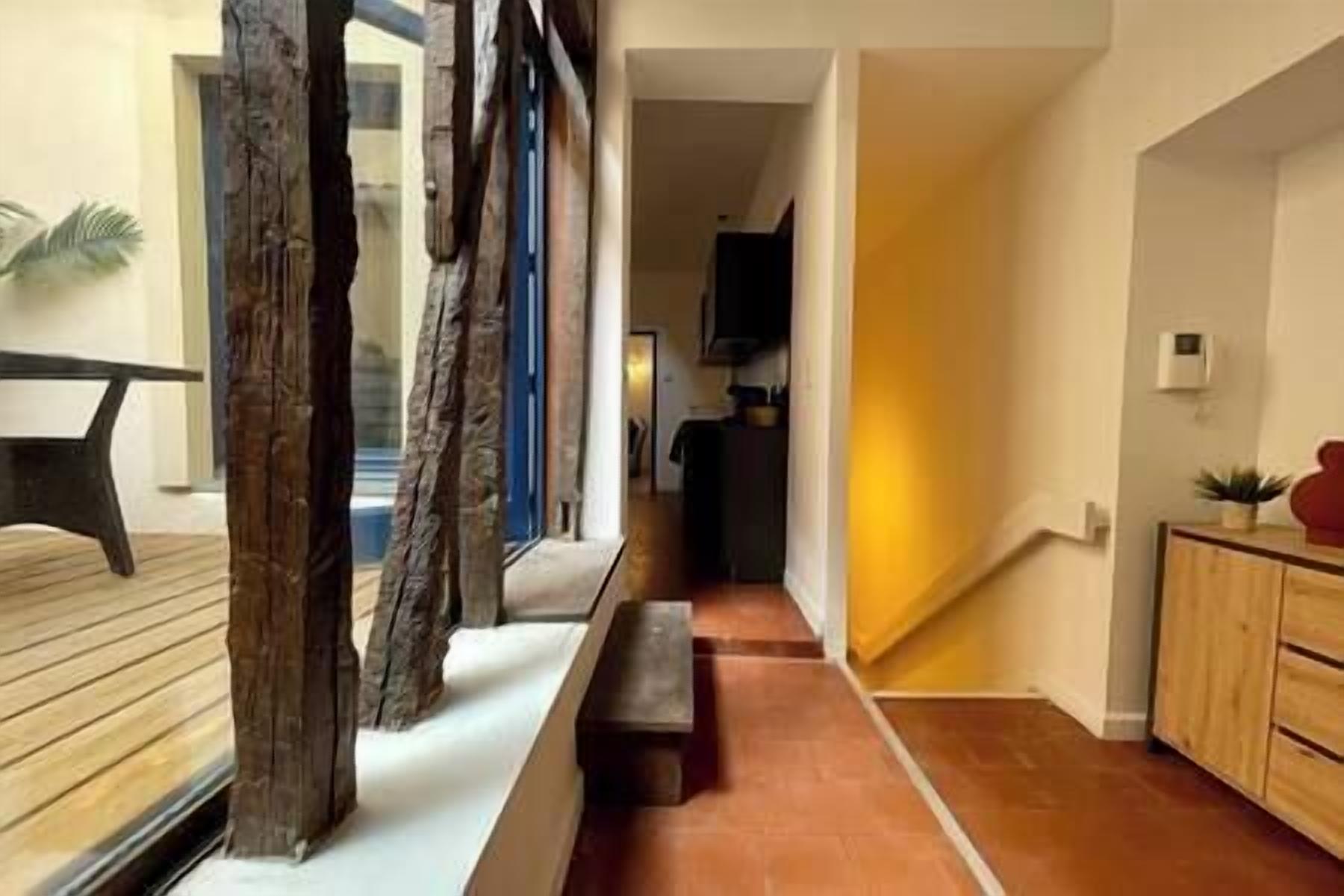 A hallway with a wooden bench, a tiled floor, and a kitchen area with cabinets and a countertop.