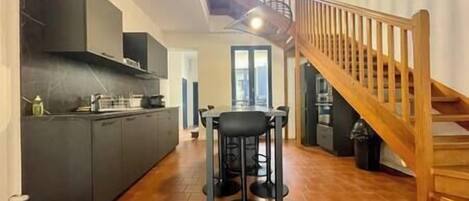A spacious kitchen with a dining area, a staircase, and a view of the outdoors.