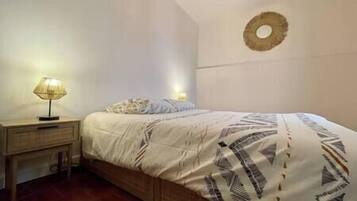 A bedroom with a bed, bedside tables, and a wall-mounted light fixture.
