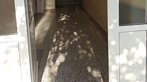 Un couloir doté d’un sol carrelé, d’un escalier et d’une porte avec un panneau en verre dépoli.