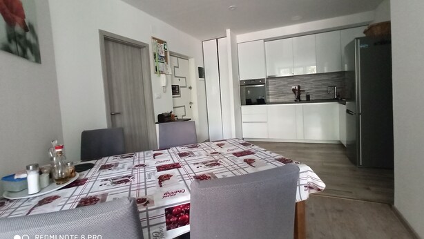 Une cuisine moderne avec des meubles blancs, un réfrigérateur en acier inoxydable et un coin repas avec une table dressée pour quatre personnes.