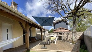 A wooden deck with a table and chairs, a hammock, and a patio umbrella.