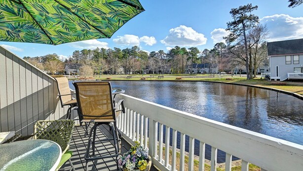 Un balcon donnant sur un lac, avec une balustrade blanche et une chaise.