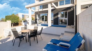 Eine moderne Terrassenanlage im Freien mit Pool, Liegestühlen und Essbereich.