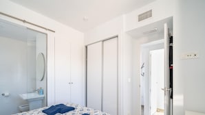 Ein modernes Schlafzimmer mit einem großen Bett, einem Badezimmer mit Duschkabine und einem begehbaren Kleiderschrank.