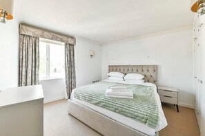A bedroom with a bed, a bedside table, a lamp, and a window with curtains.