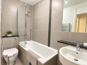 Een moderne badkamer met een bad, toilet en wastafel.