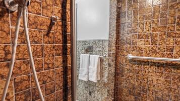A bathroom with a shower, a toilet, and a towel rack.