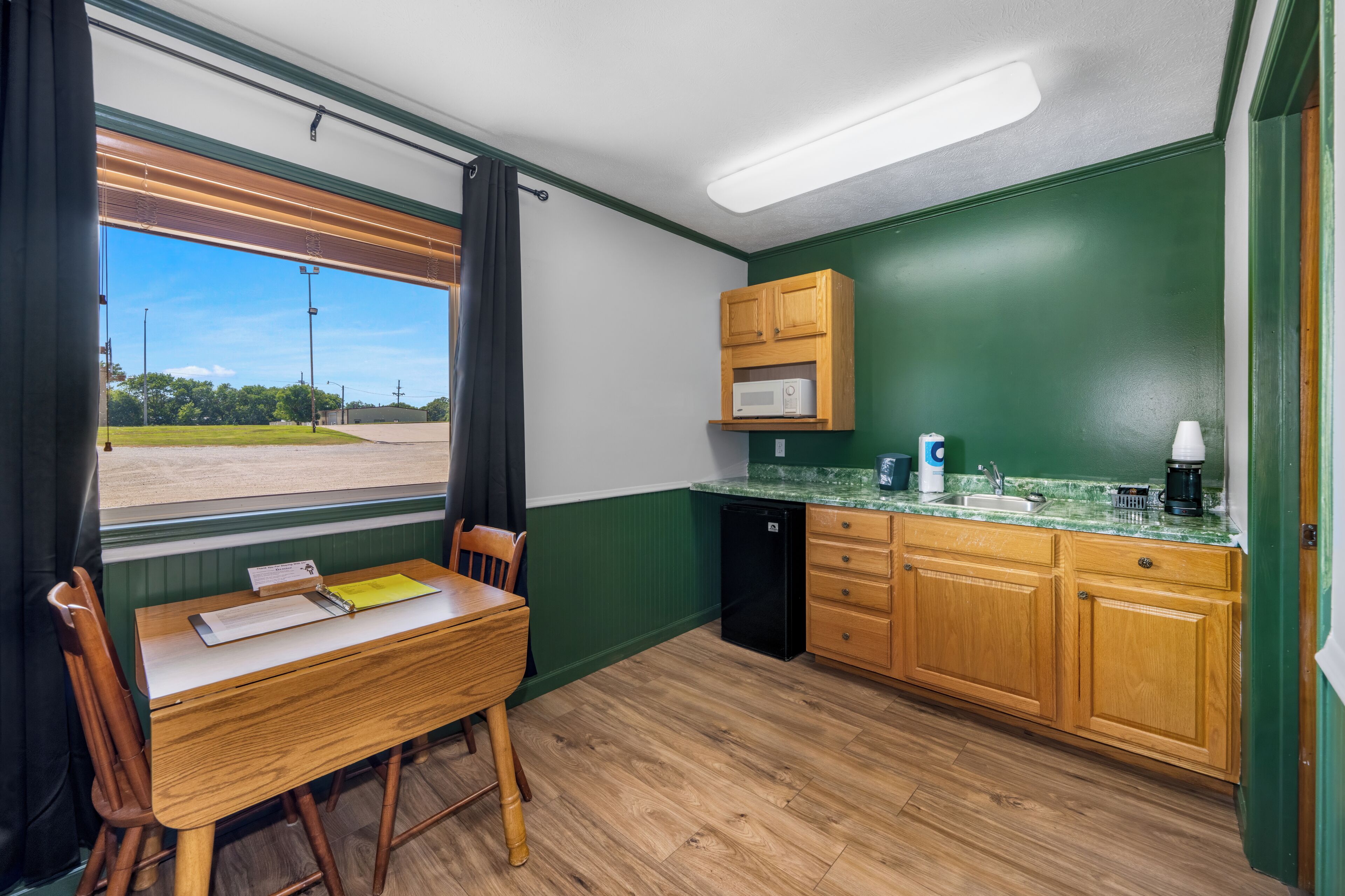 A compact kitchen with wooden cabinets, a microwave, and a sink.