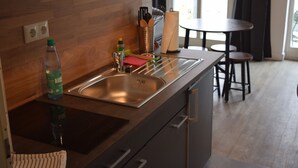 A modern kitchen with a stainless steel sink, wooden backsplash, and a dining area with a round table and two chairs. - Alstadt kiek mal wedder in  (Wismar)