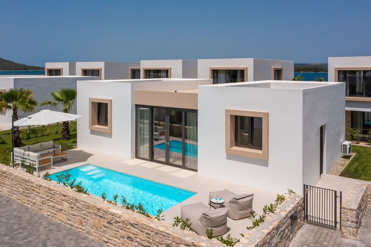 Eine moderne Villa mit Pool, Sitzgelegenheit im Freien und Meerblick.
