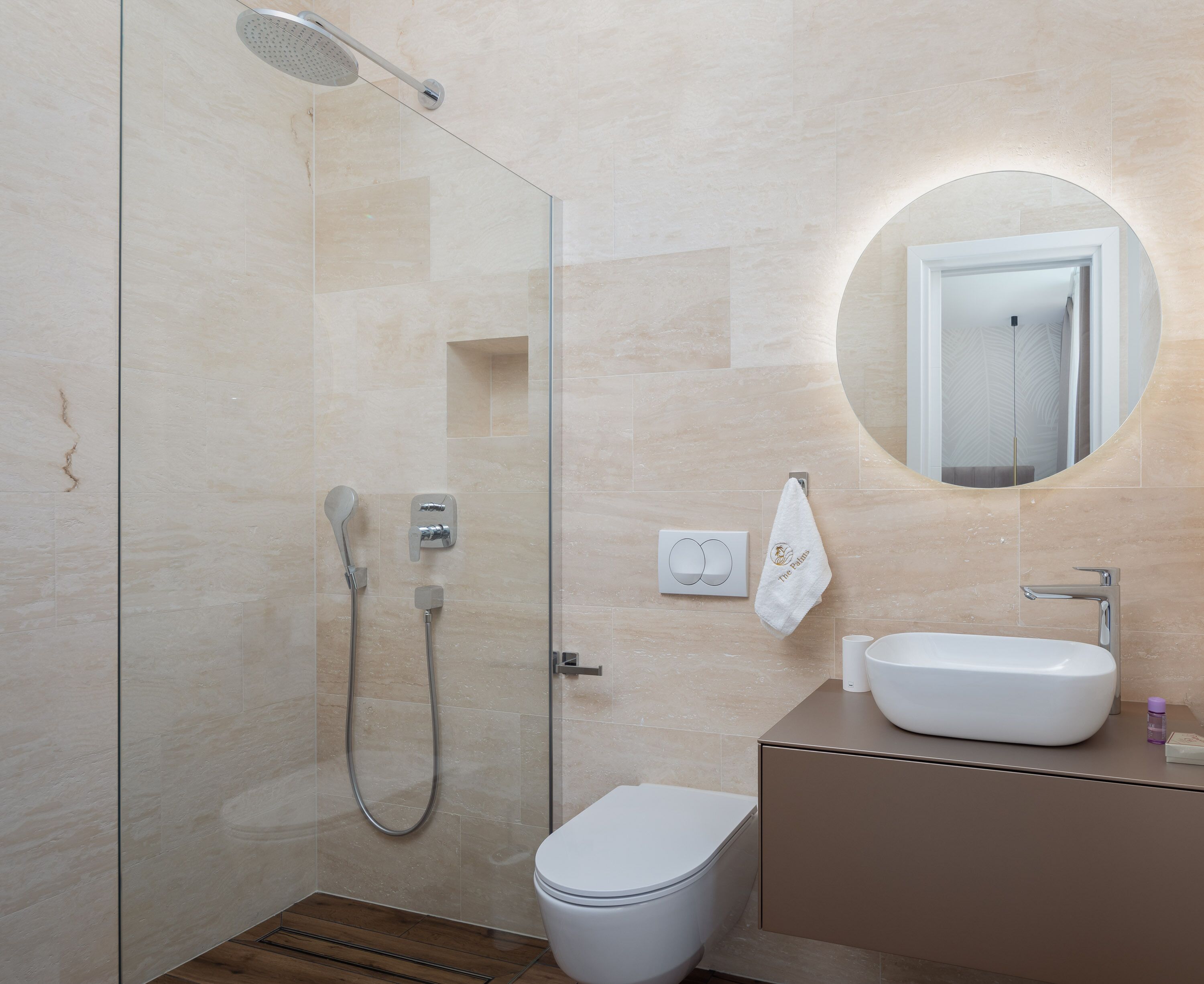 Une salle de bain moderne avec une douche à parois de verre, des toilettes blanches et un meuble-lavabo avec un évier et un miroir.
