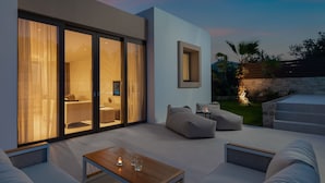 A modern outdoor living area with a sofa, a wooden table, and a glass-enclosed space with a view. - The Palms Resort (Tkon)