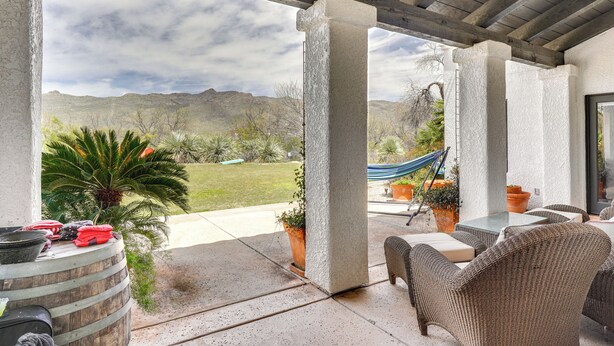 Une terrasse couverte, aménagée avec du mobilier d’extérieur, un hamac et des plantes en pot.
