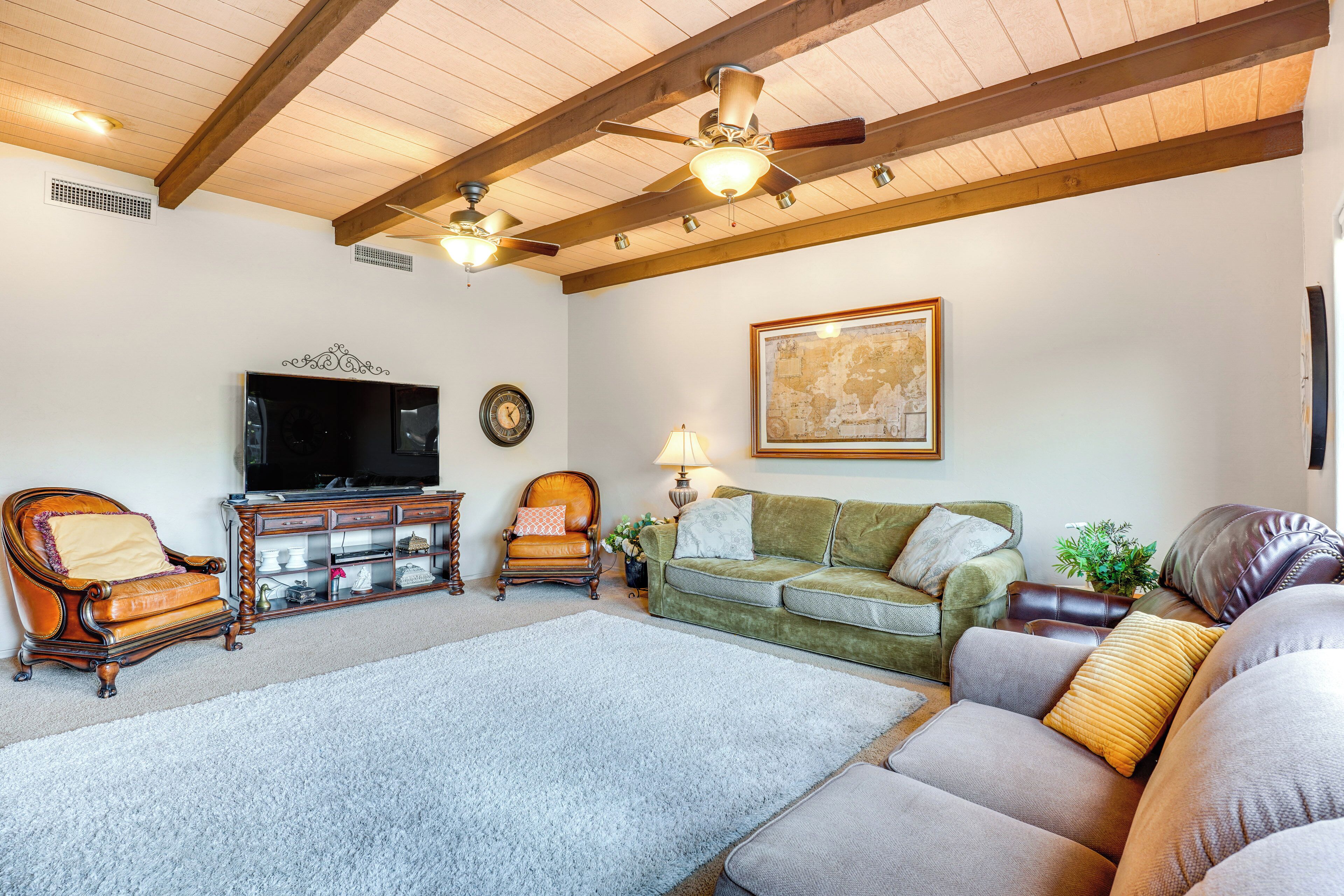A living room with a wooden ceiling, a television, a sofa, and a fireplace.