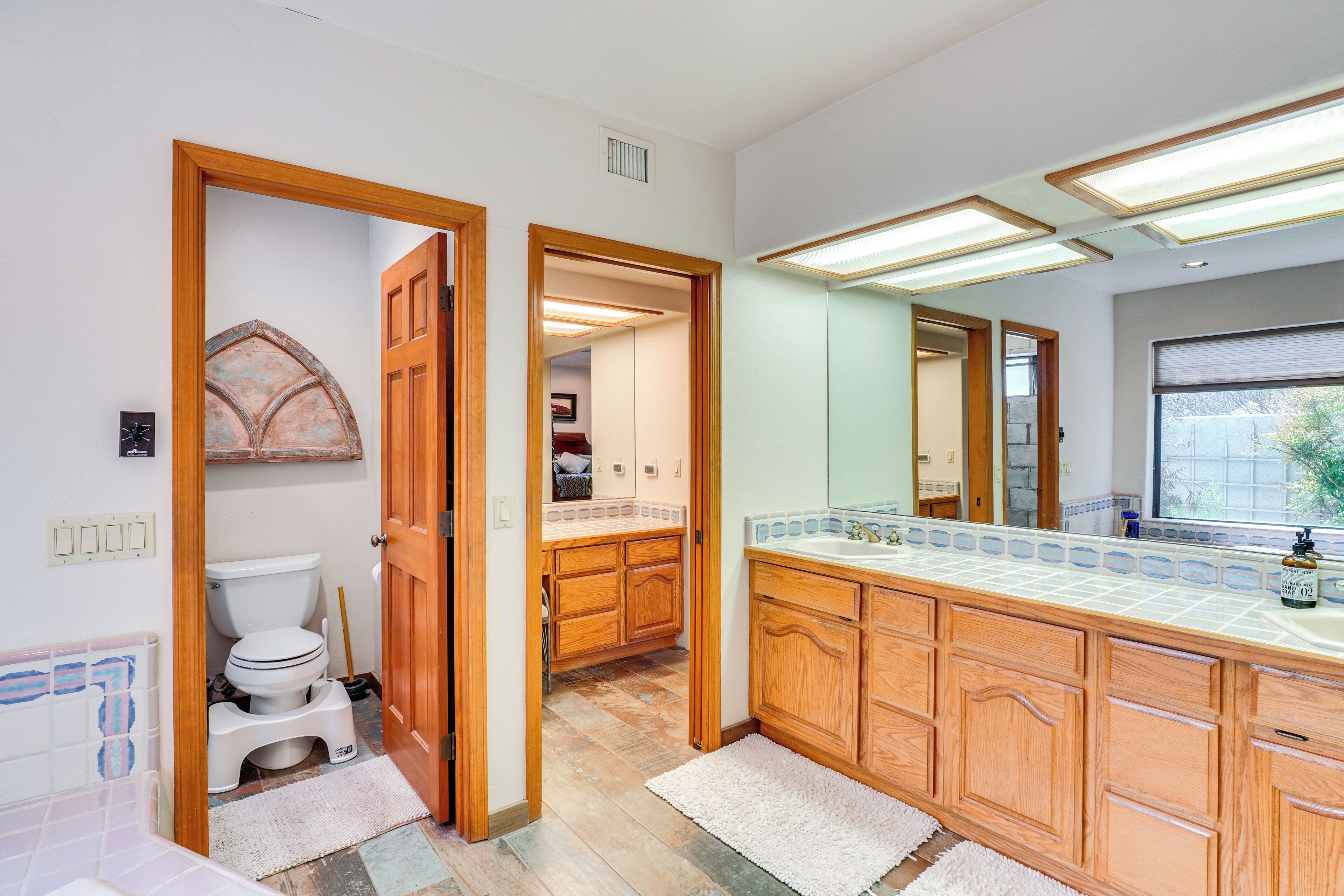 A bathroom with wooden cabinets, a white toilet, and a large mirror.