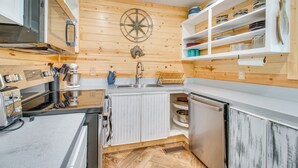 Kompakti keittiö, jossa on puuseinät, keskeinen keittiösaareke, mikroaaltouuni, pesuallas ja astianpesukone.