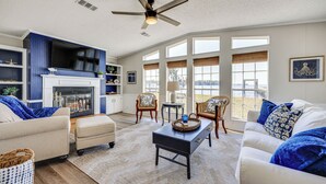 A spacious living room with a fireplace, comfortable seating, and large windows offering a view. - St Augustine Home w/ Dock & Lift on St Johns River (St. Augustine)
