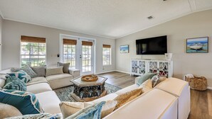 A spacious living room with a large sectional sofa, a coffee table, and a flat-screen TV mounted on the wall. - St Augustine Home w/ Dock & Lift on St Johns River (St. Augustine)