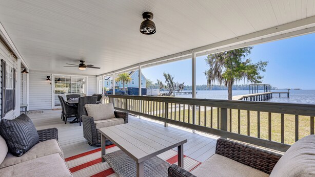 A covered outdoor area with a dining table, chairs, and a view of the beach. - St Augustine Home w/ Dock & Lift on St Johns River (St. Augustine)