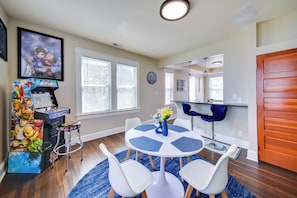 A dining area with a round table, white chairs, and a blue rug.