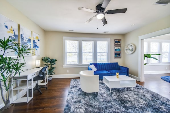 A living room with a blue sofa, white coffee table, and a ceiling fan.