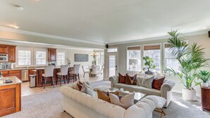 A spacious living area with a large sofa, a coffee table, and a dining area with chairs and a table. - Lake Arrowhead Home: Mountain View, Walk to Water! (Lake Arrowhead)
