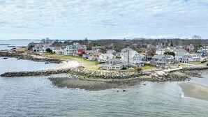 A coastal residential area with houses along the shoreline, a rocky breakwater, and a view of the sea. - Charming Westbrook Cottage, Steps to Private Beach (Westbrook)