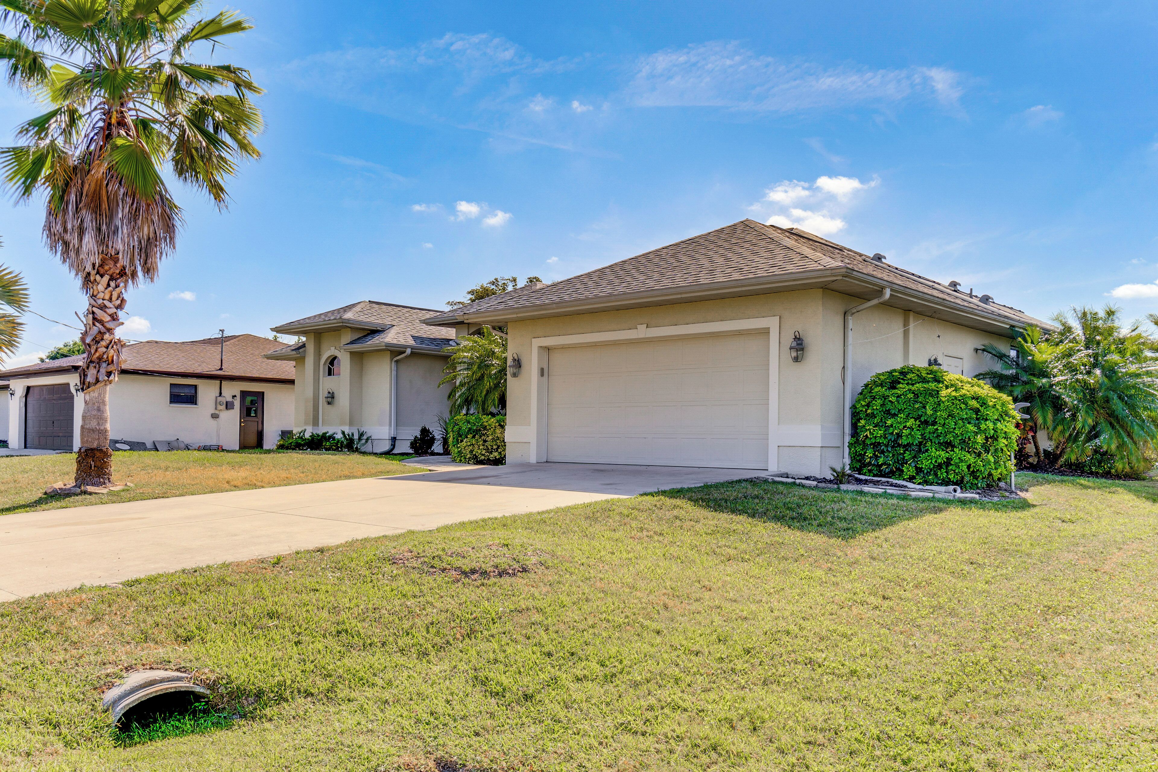 A single-story house with a garage, a front lawn, and a palm tree.
