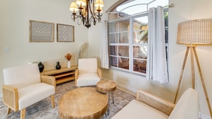 A living room with a large window, a chandelier, and two sofas. - Waterfront Port Charlotte Home - 5 Mi to Beach! (Port Charlotte)