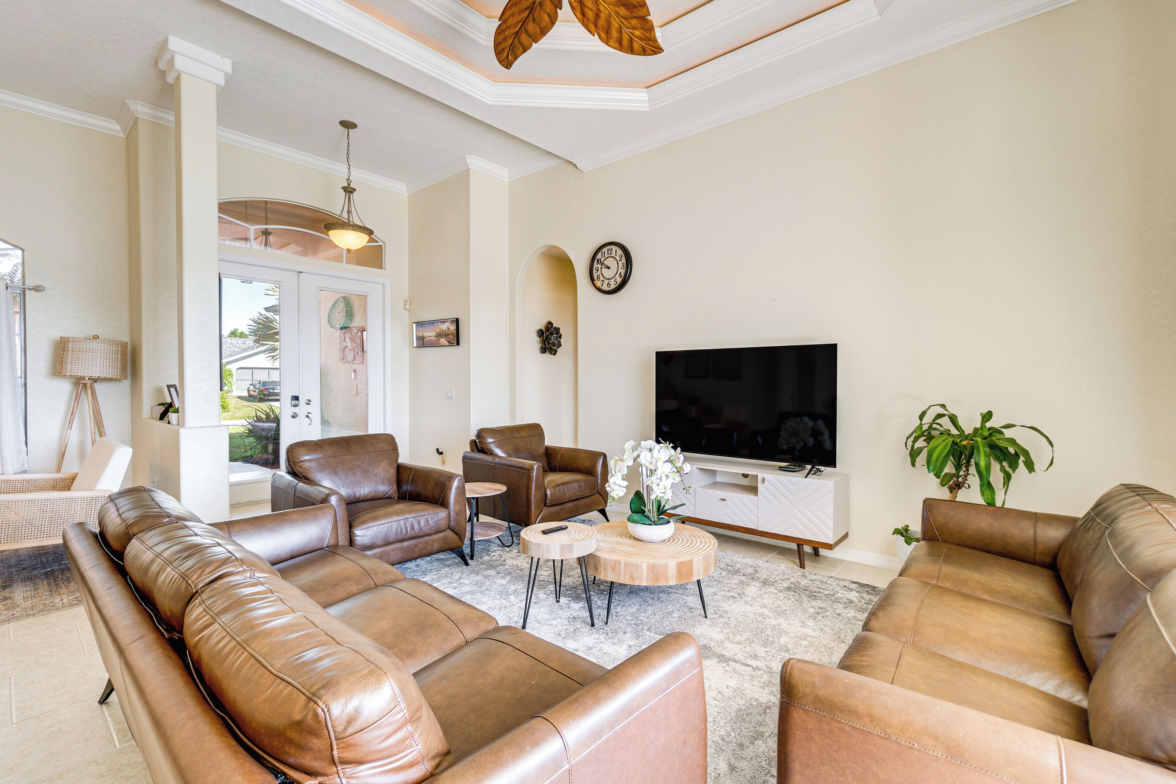 A living room with leather sofas, a television, and a potted plant.