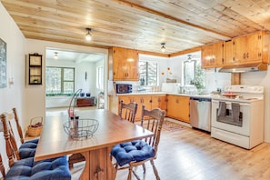 A kitchen with wooden cabinets, a dining table with blue cushioned chairs, a built-in oven, and a refrigerator.
